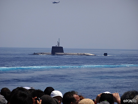 ヘリと潜水艦の訓練を見学者が見ている写真